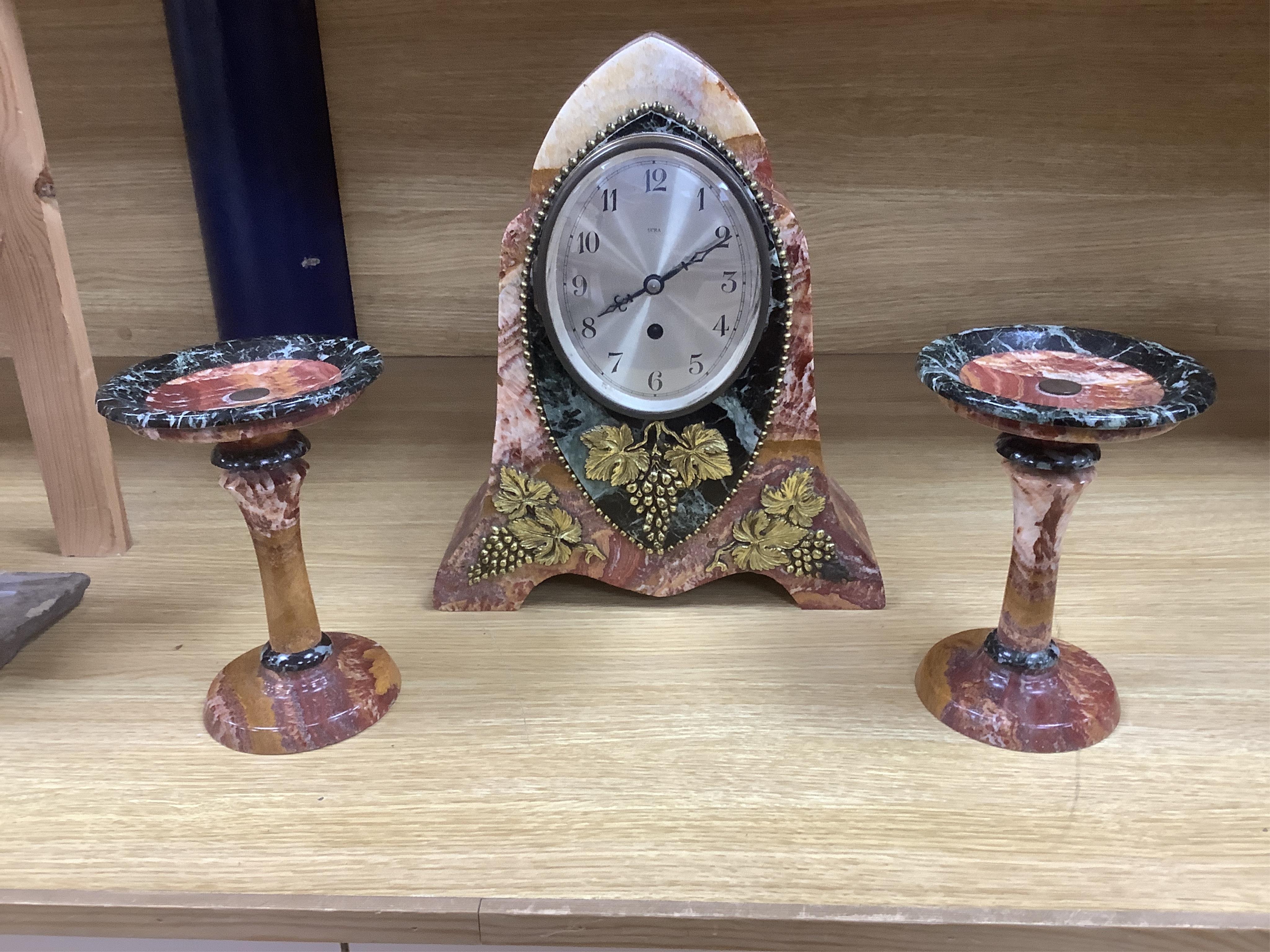 An early 20th century French rouge and black marble clock garniture with ornamental grape motif mounts to the clock and with a key. Clock 34.5 cm high